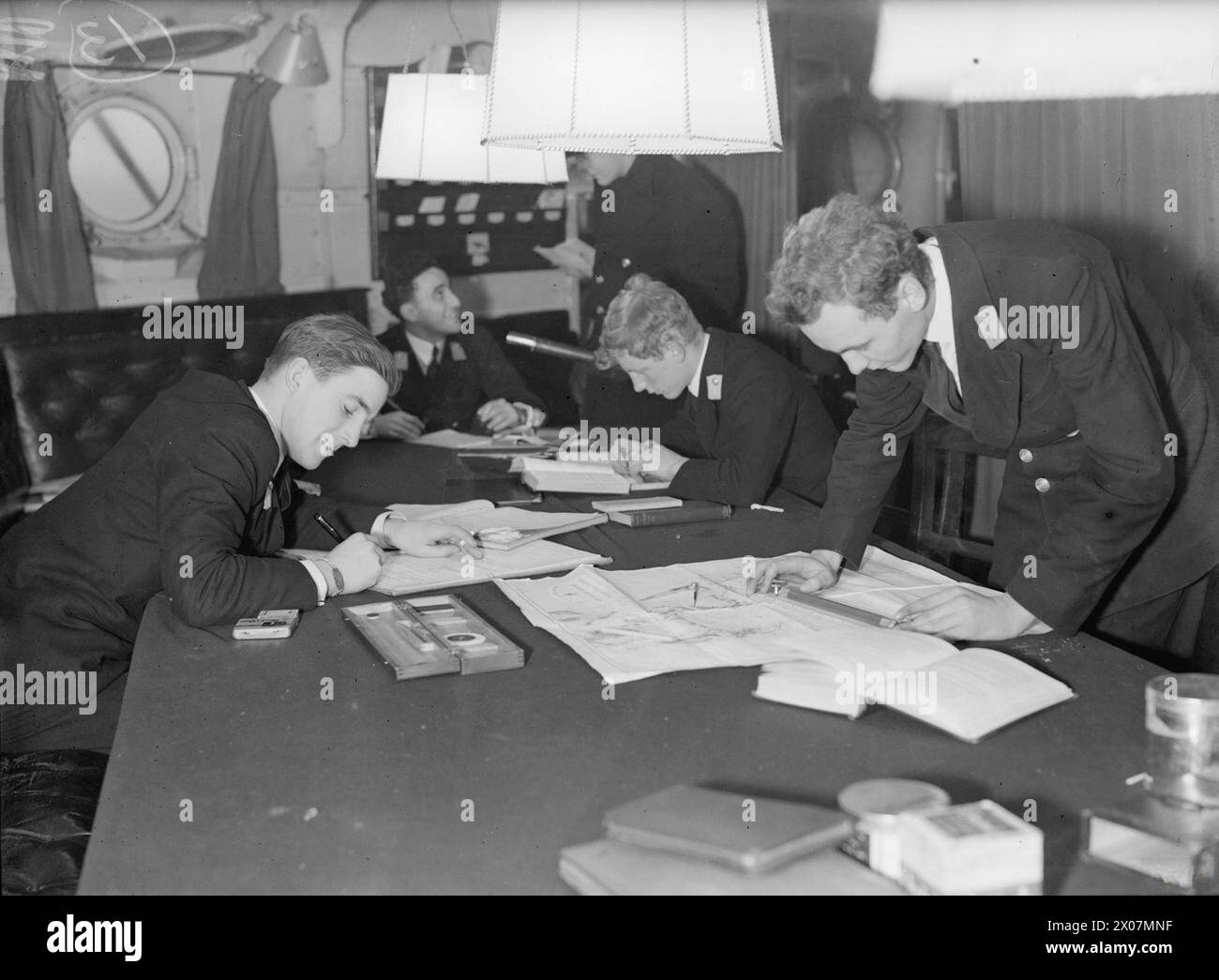 'MIDDIES' OF THE ROYAL NAVY. 3, 14 AND 18 JANUARY 1943, ABOARD HMS MALAYA, AT SCAPA FLOW. LIFE ABOARD FOR THE MIDSHIPMEN OF THE ROYAL NAVY; JUNIOR NAVAL OFFICERS WHO HAVE HAD A COURSE AT A NAVAL COLLEGE AND ARE STILL STUDYING THE THEORY AND PRACTICE OF SEAMANSHIP. - Midshipmen studying between watches in the gun room Stock Photo