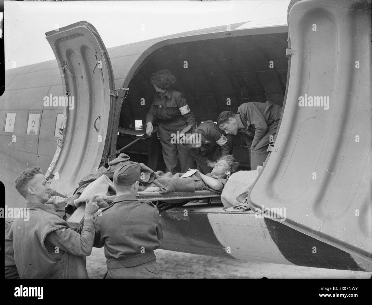 ROYAL AIR FORCE TRANSPORT COMMAND, 1943-1945. - Aircrew and WAAF nursing orderlies help to load a battle casualty on a stretcher into a Douglas Dakota Mark III of No. 233 Squadron RAF at B2/Bazenville, Normandy. The RAF's first 'casevac' flights to France were mounted by Dakotas of No. 46 Group on 13 June 1944, and the WAAF nursing orderlies pictured were the first women to be employed on these duties  Royal Air Force, Maintenance Unit, 235, Royal Air Force, Women's Auxiliary Air Force Stock Photo