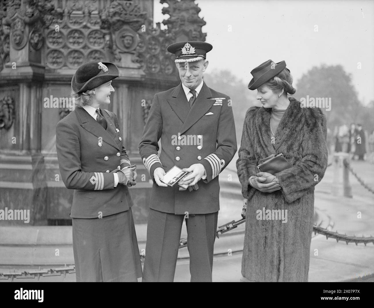 NAVAL HEROES AT HOLYROOD. 26 SEPTEMBER 1945, NAVAL OFFICERS WERE DECORATED BY HM THE KING AT AN INVESTITURE IN HOLYROOD HOUSE, EDINBURGH. - Captain Duncan Hill, RN, of Lemington Spa showing his DSO to his wife, Chief Officer R M Hill, WRNS, and sister-in-law Mrs R R Uprichard of St Andrews Stock Photo