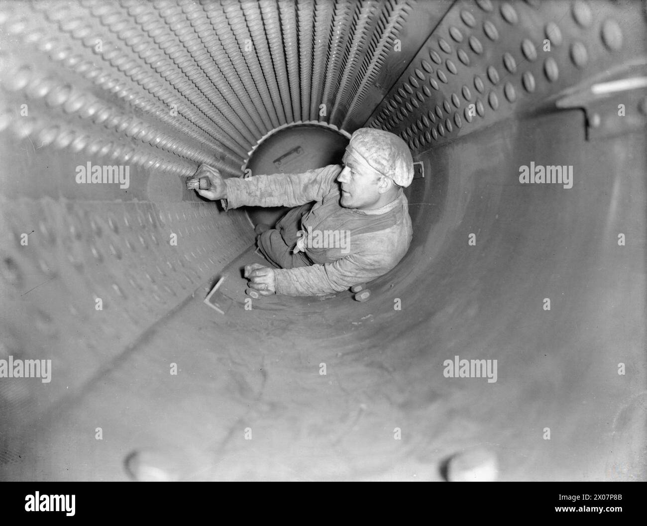 THE ROYAL NAVY DURING THE SECOND WORLD WAR - A stoker cleaning inside the boiler of the cruiser HMS CURACOA at Rosyth. The inside of the boiler is 4 feet in diameter and 12 feet long  Royal Navy, CURAÇAO (HMS) Stock Photo