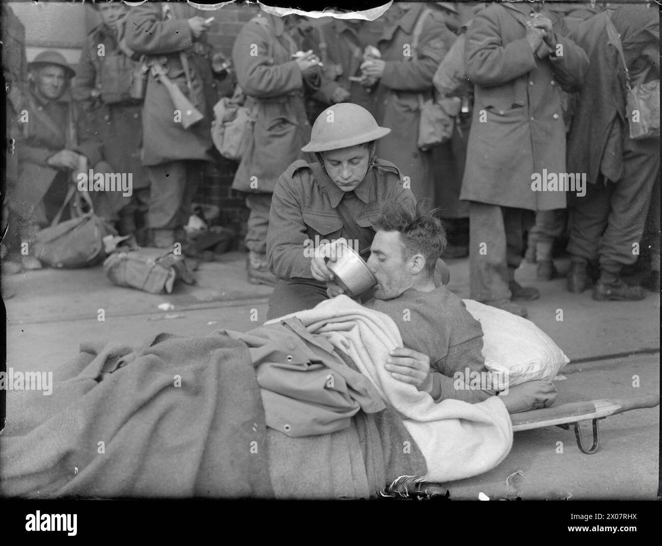 A wounded British Army soldier receives a drink on a stretcher at the ...