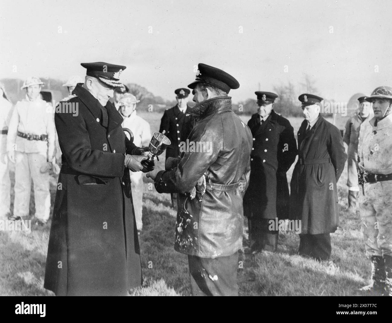 NAVAL AIR STATION FIRE FIGHTERS. 9 DECEMBER 1944, LEE-ON-SOLENT ROYAL NAVAL AIR STATION. THE FINALS OF THE ROYAL NAVAL AIR STATIONS (SOUTHERN) FIRE FIGHTING COMPETITION. THE FINALISTS WERE CREWS FROM ROYAL NAVAL AIR STATION EASTLIEGH (HMS RAVEN) AND ROYAL NAVAL AIR STATION HENSTRIDGE (HMS DIPPER), THE FORMER TEAM BEING THE WINNERS. IN THE COMPETITION THE CREWS HAVE TO PUT OUT AN AIRCRAFT FIRE AND RESCUE A DUMMY FROM THE COCKPIT OF THE AIRCRAFT. - Rear Admiral C V Robinson, Flag Officer Naval Air Stations, presenting the Cup to the winning team Stock Photo