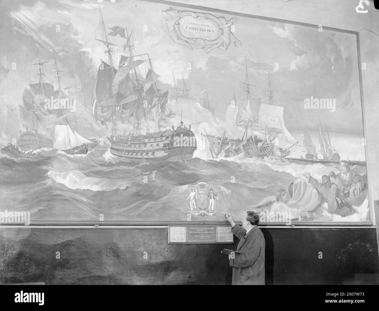 FAMOUS SCOTTISH ARTISTS VISIT A NAVAL CANTEEN. 21 JANUARY 1942, ROSYTH. SEVERAL WELL KNOWN ARTISTS VISITED A ROYAL NAVAL AND ROYAL MARINE CANTEEN, AND PAINTED THREE PANELS BY WAY OF A DECORATION. THE ARTISTS WERE MRS HASWELL MILLER, ARSA, ANNE REDPATH (NOW MRS MICHIE) AND MRS MARY ARMOUR, ARSA. MR W C HUTCHINSON ALSO VISITED THE CANTEEN TO SIGN HIS PAINTING OF THE BATTLE OF CAMPERDOWN. - Mr W C Hutchinson signing his painting of the Battle of Camperdown Stock Photo