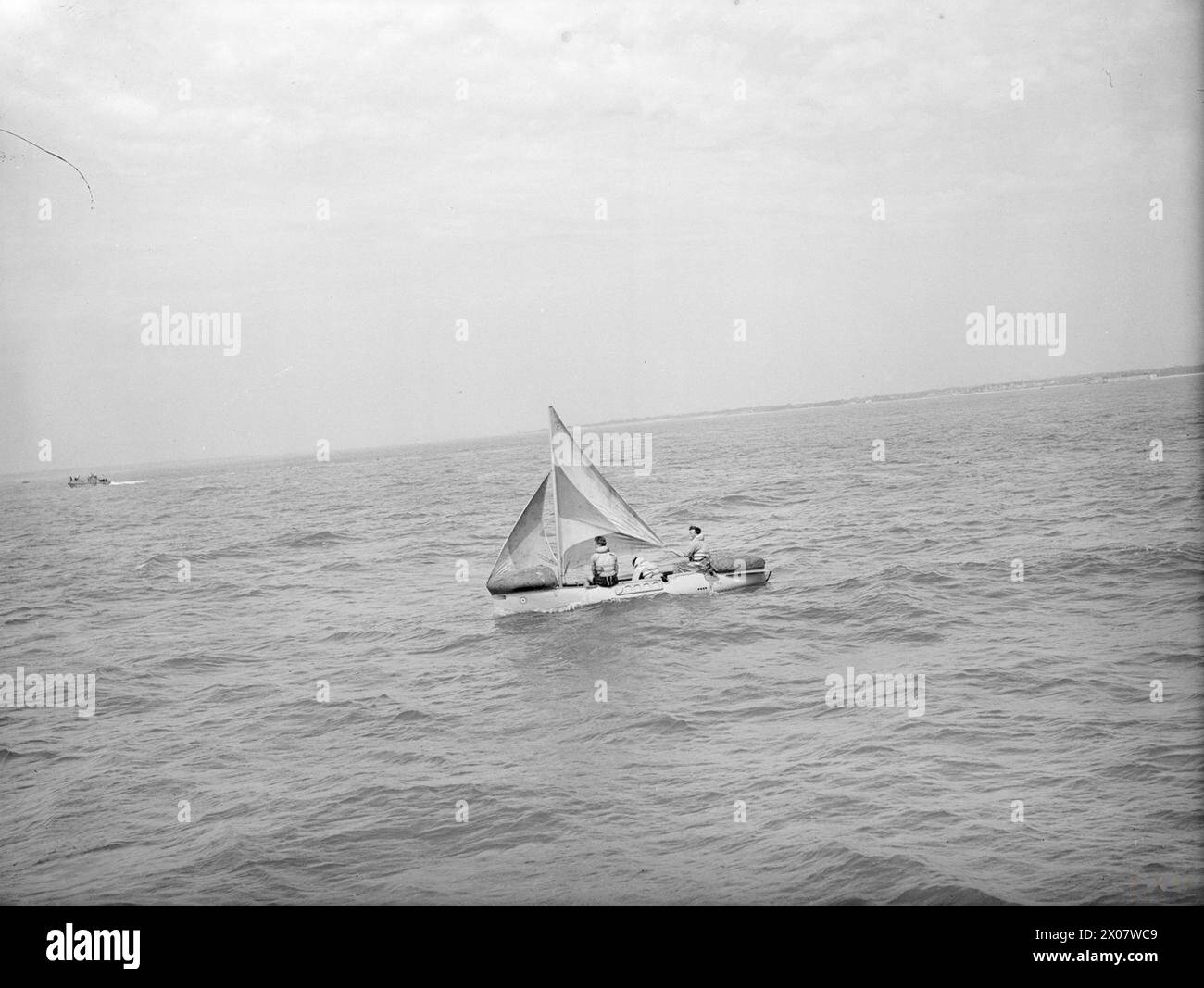 LIFEBOAT DROPPED FROM AIR. 13 JULY 1945, LEE-ON-SOLENT. THE DEMONSTRATION DROP OF THE NAVY'S AIRBORNE LIFEBOAT, 17 FT, 9 INS LONG, WHEN IT WAS DROPPED BY PARACHUTE TO AN AIR CREW WHO WERE SUPPOSED TO HAVE FORCED LANDED INTO THE SEA. THE LIFEBOAT, SELF-RIGHTING, AND SELF-BALING IS EQUIPPED WITH SAILS AND AN OUTBOARD ENGINE WHICH GIVES IT A RANGE OF 120 MILES AT 4 KNOTS. - The 'air crew' got the lifeboat underway with gib and mainsail set Stock Photo