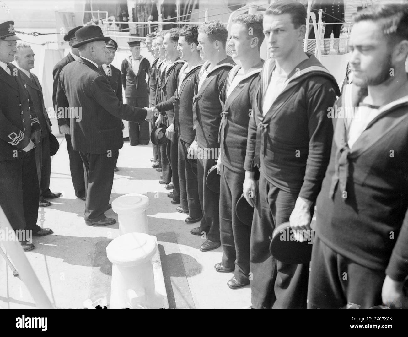 NEW ZEALAND HIGH COMMISSIONER VISITS THE NEW ZEALAND CORVETTE HMNZS ARBUTUS. 19 JUNE 1944, GREENOCK. - Mr Jordan, the High Commissioner, shaking hands with members of the ship's company of the ARBUTUS. Left to right in this rank are: Able Seaman S E Ogg, from Dunedin; Ordinary Seaman B M McRobie, from Wellington; Able Seaman E W Sharp, from London (England); Able Seaman W E Brown, from Auckland; Able Seaman V G Saunders, from Tauranga; Ordinary Seaman J L Carmine, from New Plymouth; Ordinary Seaman J Mains, from Sawyers Bay; Ordinary Seaman B Couchman, from Wanganui; Ordinary Seaman W Berghan, Stock Photo