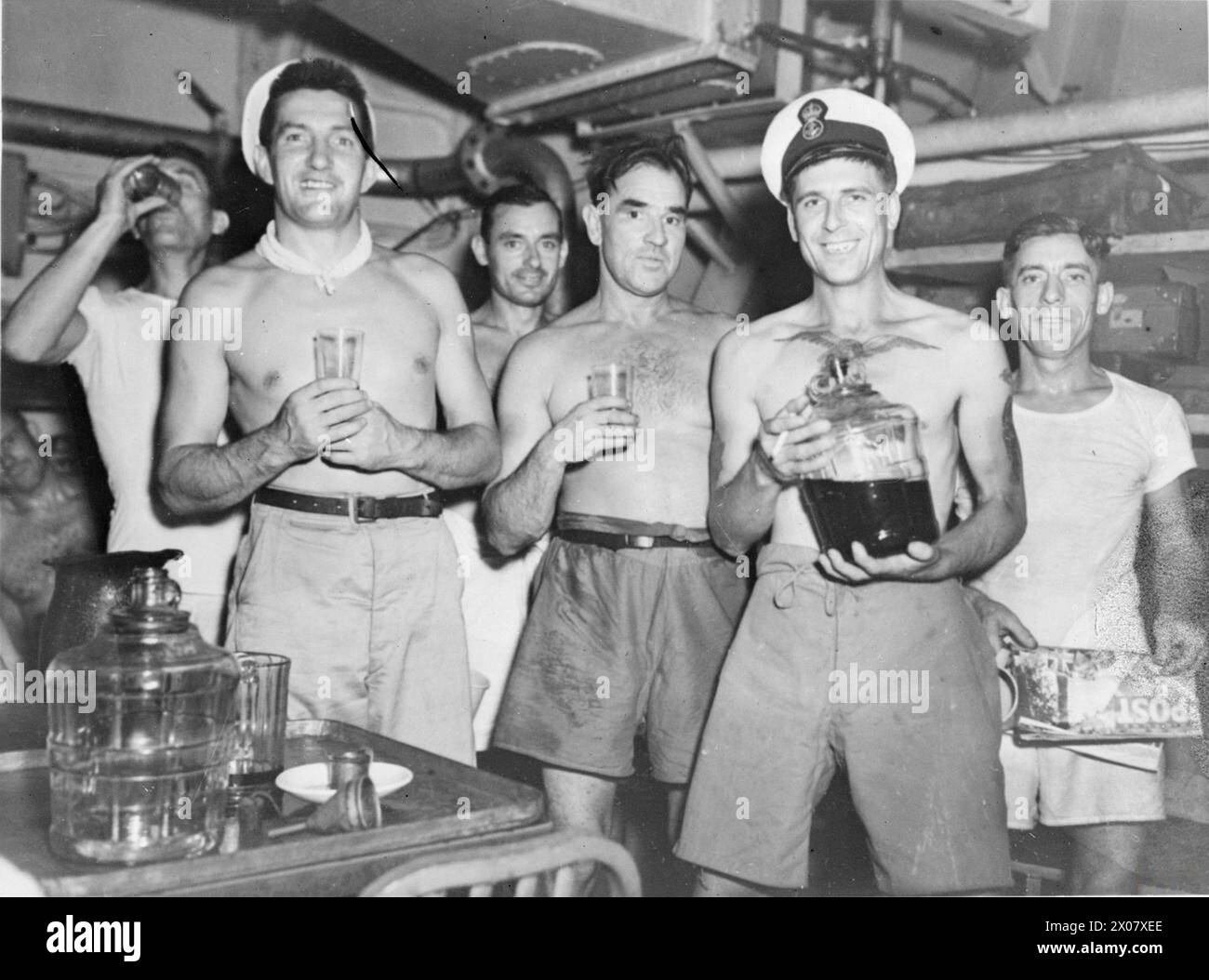 LIBERATED POW'S ON THEIR WAY HOME. 4 SEPTEMBER 1945, ON BOARD THE ESCORT CARRIER HMS SPEAKER AS IT CARRIED HUNDREDS OF BRITISH PRISONERS OF WAR LIBERATED FROM TOKYO CAMPS TO MANILLA, THE FIRST STAGE IN THEIR JOURNEY HOME. - These ex-prisoners of war drink their first tot of rum since 1941. Left to right: PO Leonard Soper, captured in HMS TAMAR when Hong Kong fell on Christmas 1941; PO Callohane, of Skibbereen, Eire; Yeoman Frederick Mitchell of Newcastle-under-Lyme, Staffs; PO Geoffrey Josey, of Newbury, Berkshire; and PO William Mitchell of Milton, Southsea, Hants Stock Photo