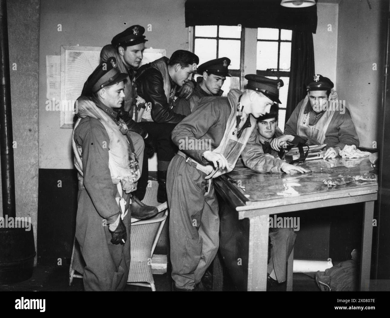 Lt. Col. Chesley G. Peterson, commanding officer of the 4th Fighter Group, is pictured in Britain inspecting a map with his flight group before a raid during 1942-1945. Stock Photo