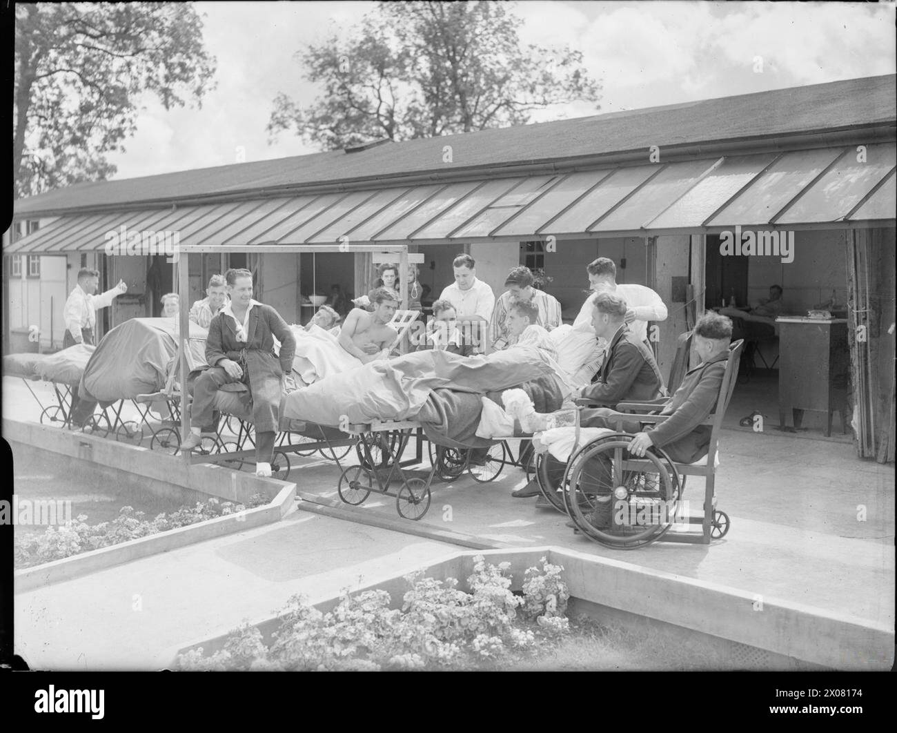 REHABILITATION OF BRITISH SOLDIERS FROM NORMANDY: THE WORK OF THE ROBERT JONES AND DAME AGNES HUNT ORTHOPAEDIC HOSPITAL, OSWESTRY, SHROPSHIRE, ENGLAND, UK, 1944 - A group of men share a joke as they relax in the sunshine on the verandah of the Robert Jones and Dame Agnes Hunt Orthopaedic Hospital Oswestry. According to the original caption, sitting in the open air is part of their treatment Stock Photo