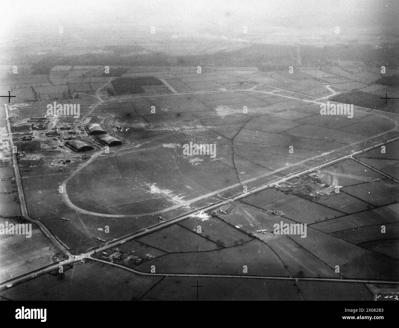 ROYAL AIR FORCE BOMBER COMMAND, 1939-1941. - Oblique aerial view of RAF Swinderby, Lincolnshire, looking south-south-west. Vickers Wellingtons belonging to Nos. 300 and 301 Polish Bomber Squadrons RAF can be seen parked on the airfield and on the circular pans of two three-spurred dispersals constructed across the Fosse Way (A46) in the foreground.On the left, a public road runs eastward from Halfway Houses (lower left) to Lane Moor Lane, dividing the airfield technical site and hangars from the domestic site (off left)  Royal Air Force, 1 Camouflage Unit, Polish Air Force, Polish Air Force, 3 Stock Photo