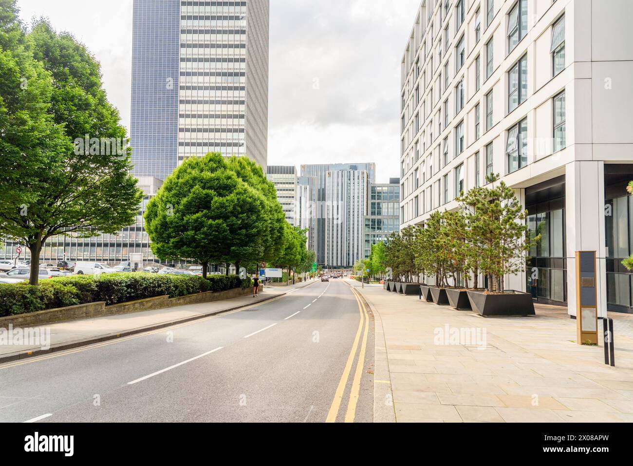 Street lined with modern office buildings and parking lots in a city centre on a cloudy summer day Stock Photo