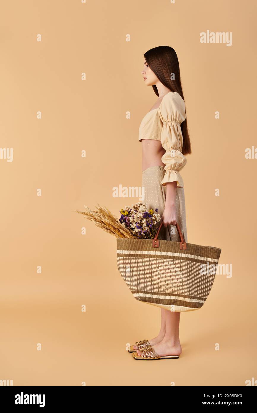 A young woman with long brunette hair elegantly holds a basket filled with colorful flowers, exuding a vibrant summer mood. Stock Photo