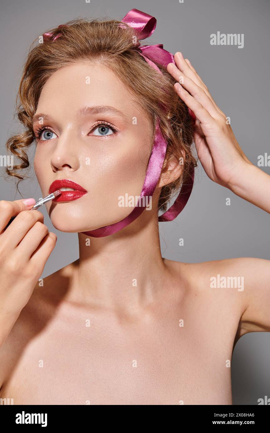 A young woman with classic beauty stands gracefully, the soft pink ribbon around her neck adding a touch of elegance. Stock Photo