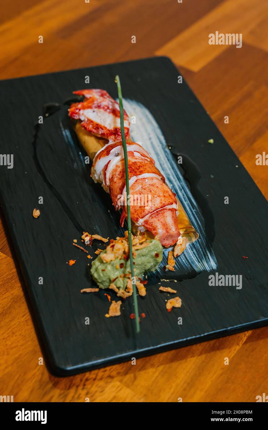 A succulent lobster tail is elegantly plated with artistic garnishes on a slate board, showcasing gastronomic finesse Stock Photo