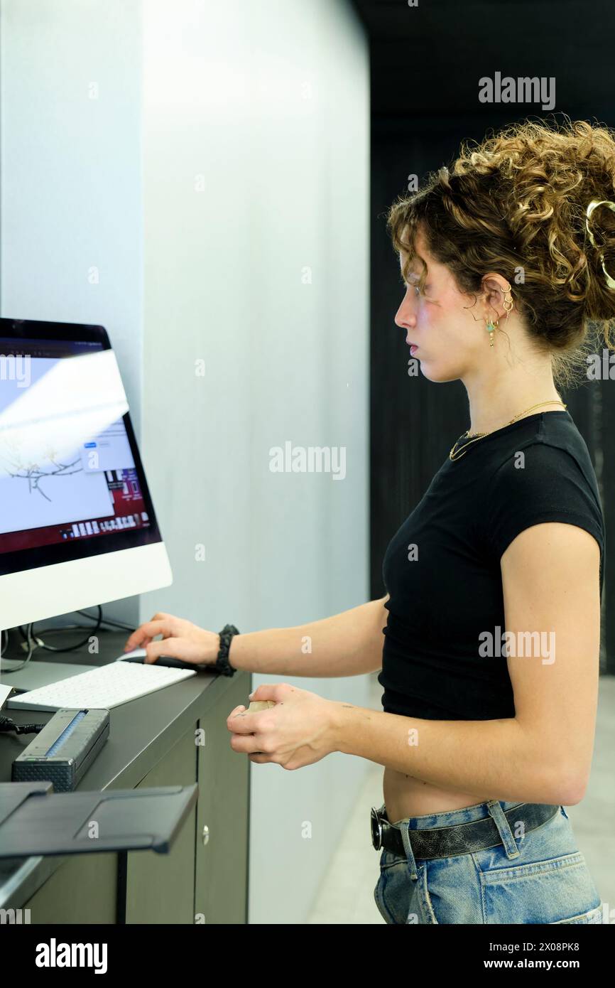 Side view of focused woman uses a computer at a contemporary workplace ...