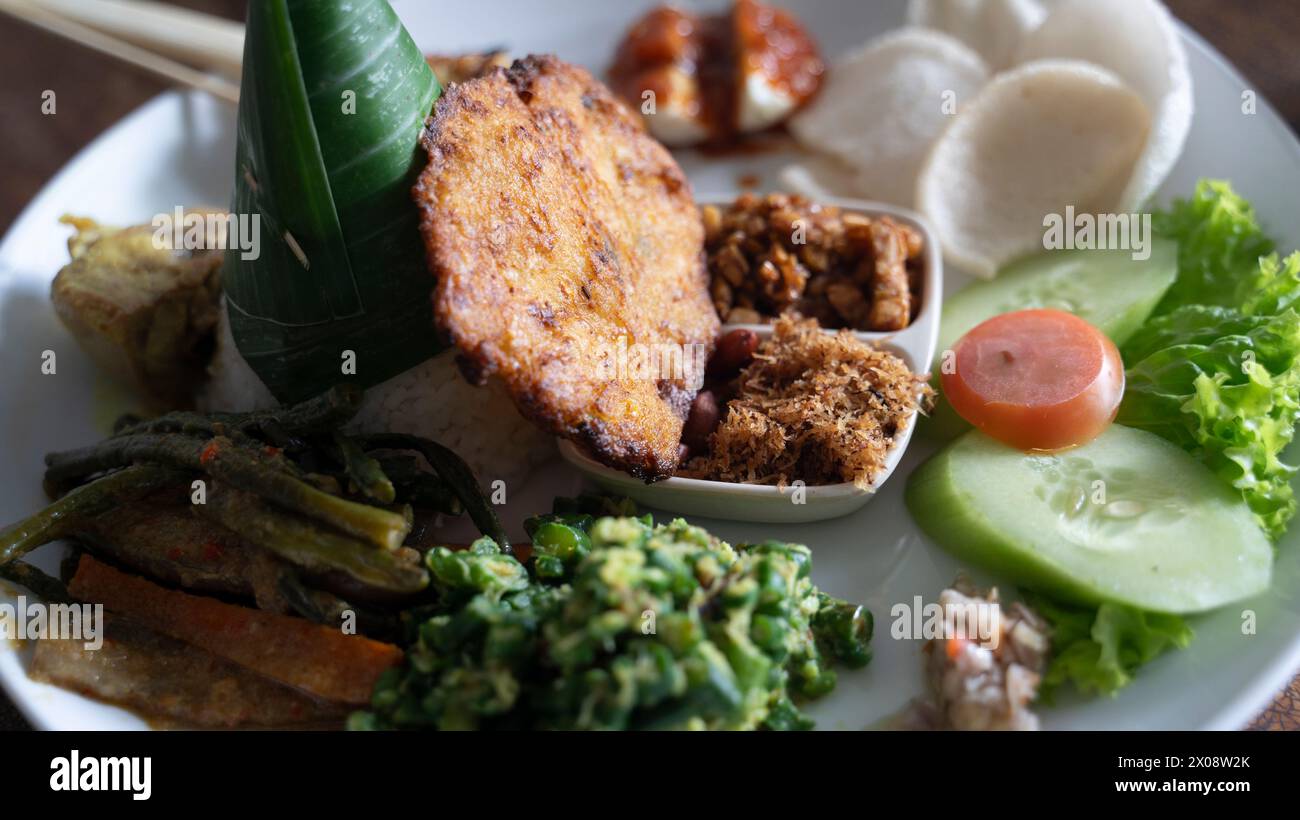 Traditional Balinese Nasi Campur with multiple dishes on white plate Stock Photo