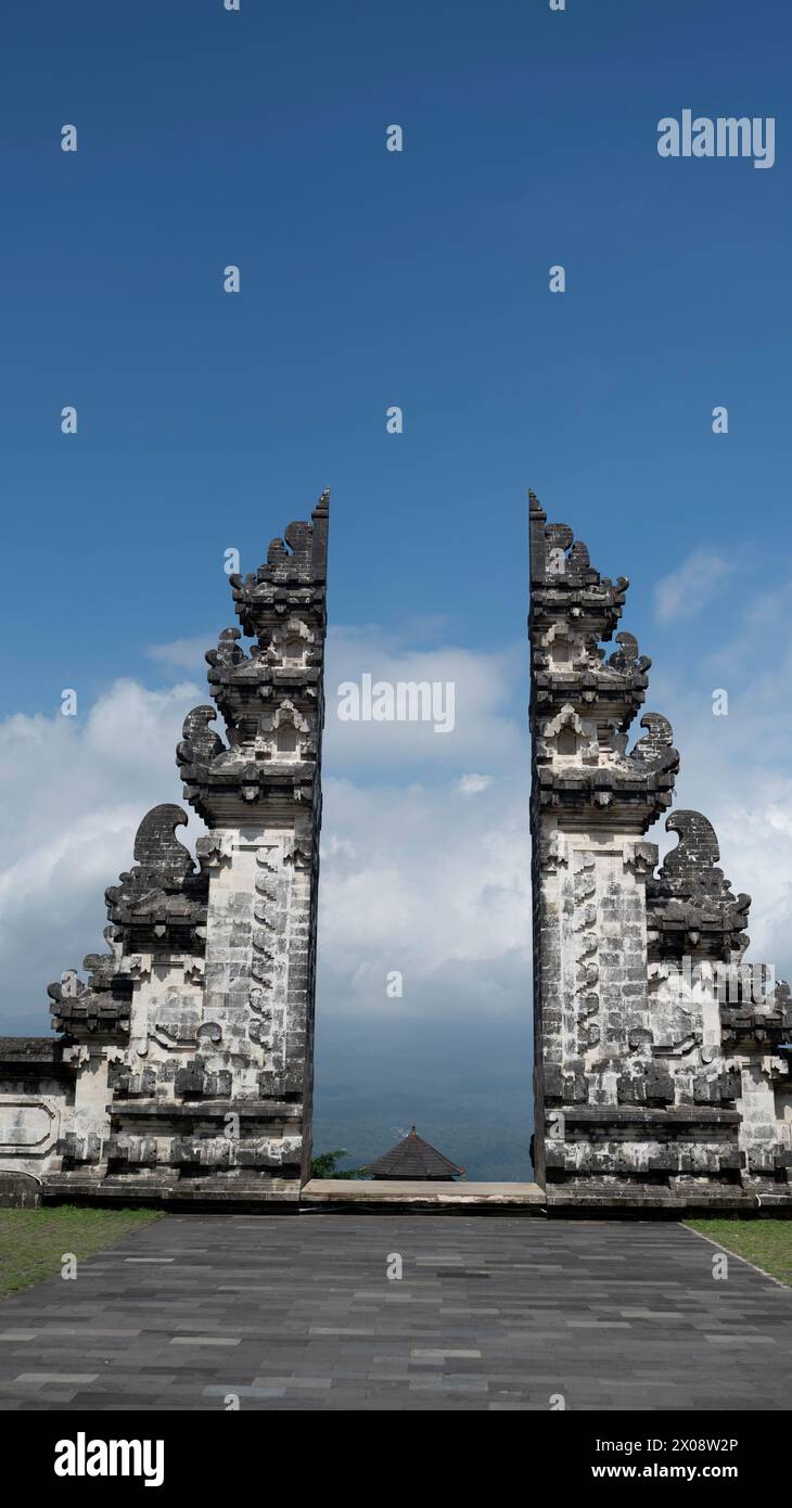 An imposing view of the traditional Balinese split gate (Candi Bentar) at Pura Lempuyang temple, Bali, with a backdrop of cloudy skies Stock Photo