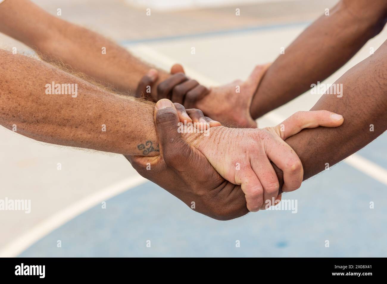 Close-up of multiethnic basketball players' hands gripping each other in a circle, displaying a powerful symbol of team commitment and trust Stock Photo