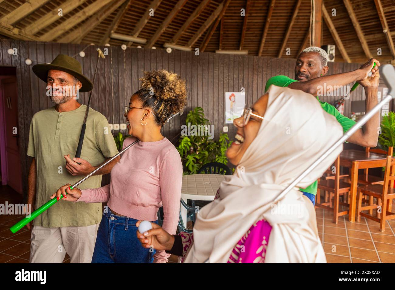 A diverse group of friends share laughter and good times at an indoor mini golf course. Stock Photo