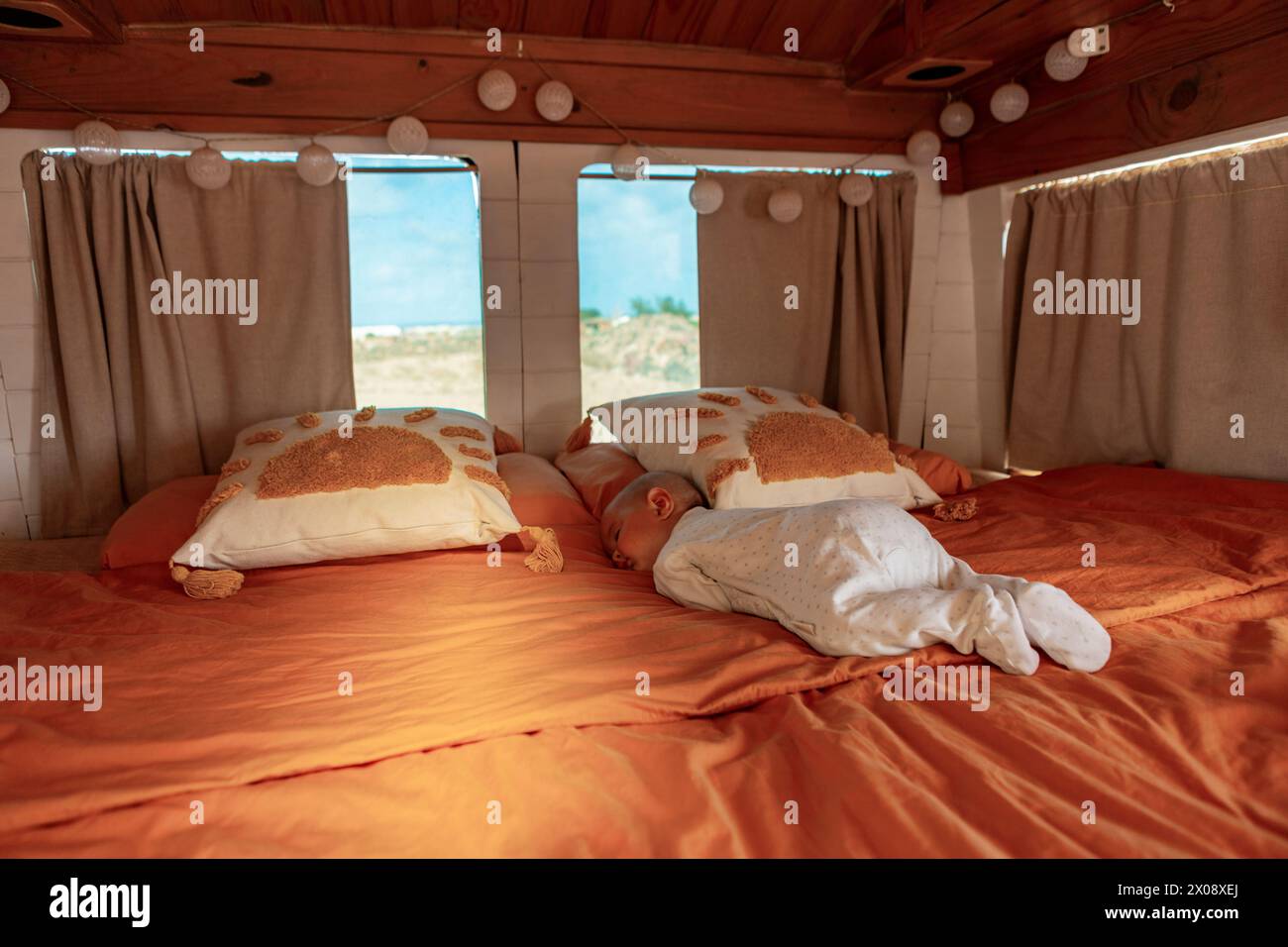 Van life family with custom-built facilities, living all year round in their adapted home on wheels with a man, woman, baby, and boy. Stock Photo