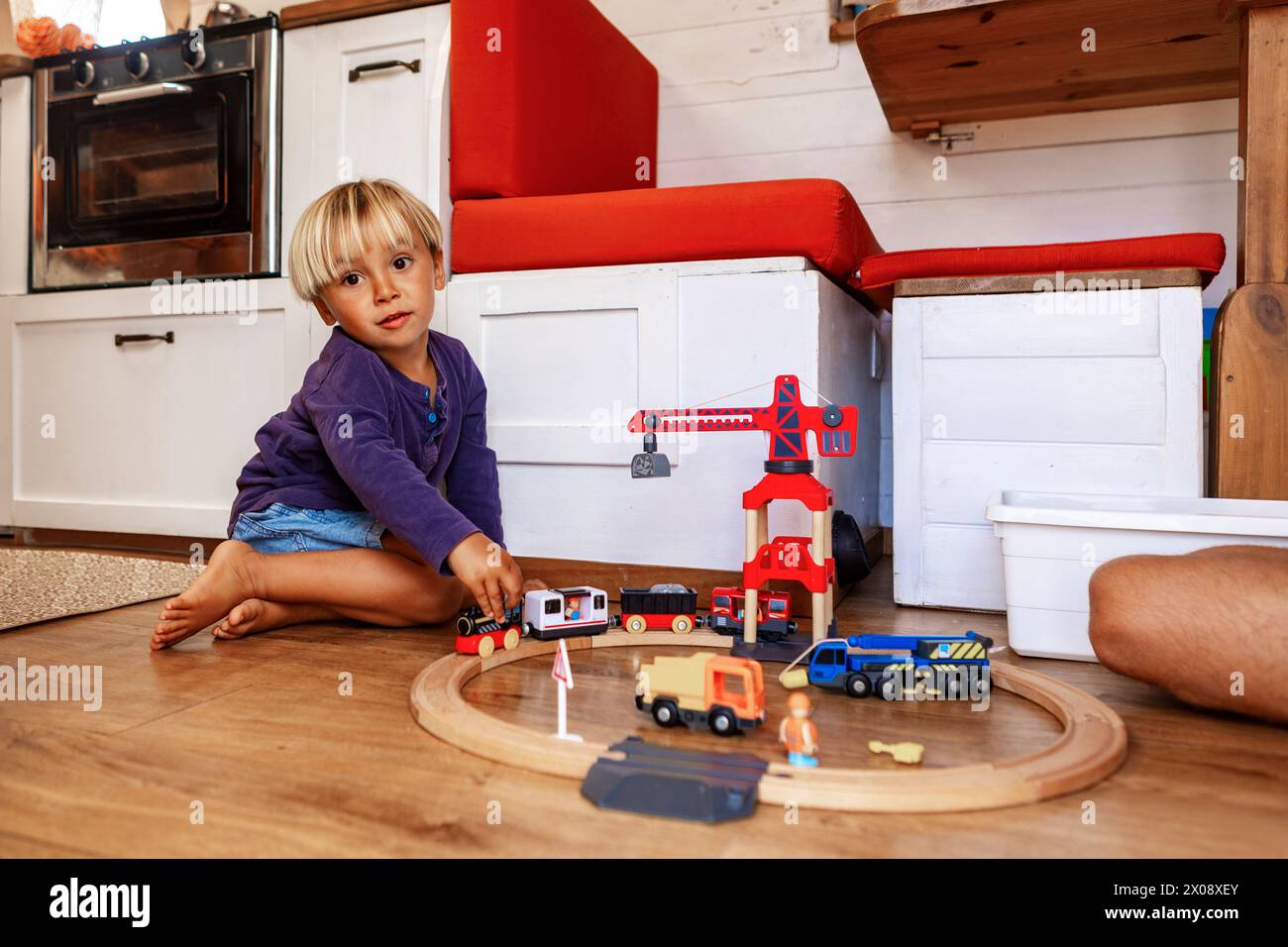 A young child plays with toys inside the cozy interior of a van, showcasing a family's customized tiny home on wheels, complete with living amenities. Stock Photo