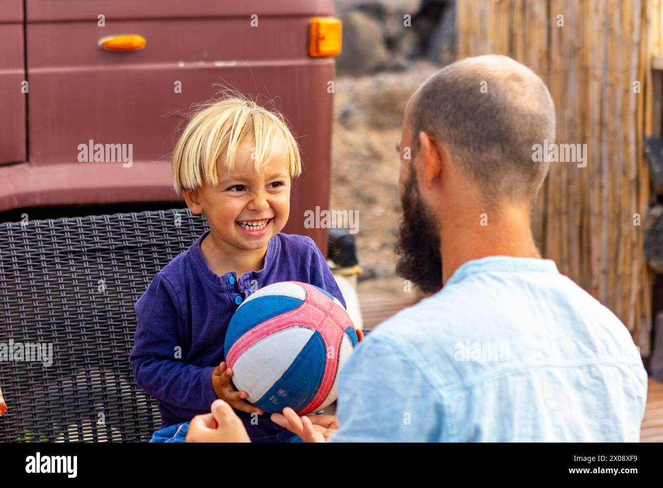 Heartwarming family time captured as a young boy shares a playful moment with his father beside their home on wheels, showcasing their unique van life Stock Photo