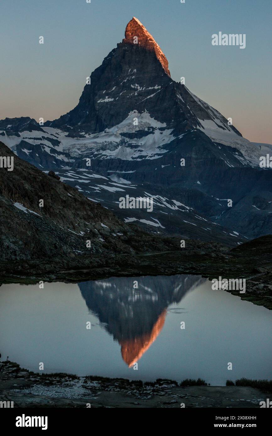 Serene twilight at Riffelsee Lake with the iconic Matterhorn reflected on the calm water surface in Zermatt, Switzerland Stock Photo