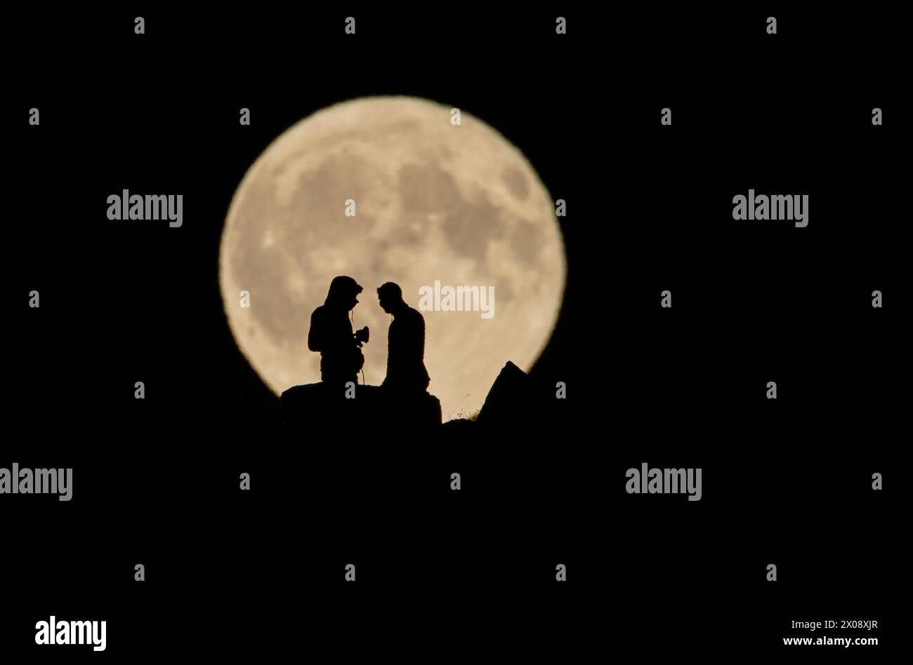 A romantic silhouette of a couple on a cliff, sharing a moment under ...