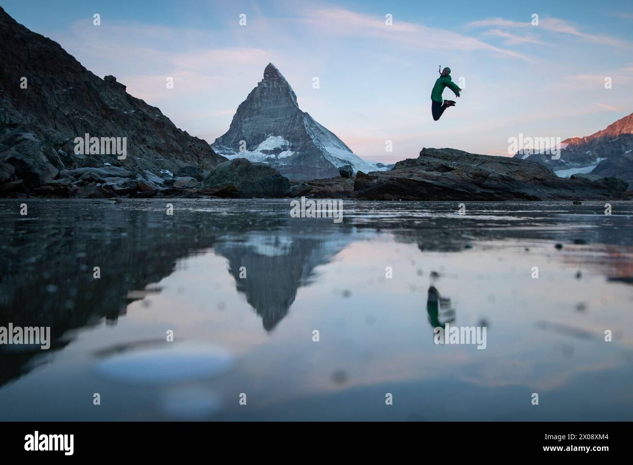 An individual is captured mid-jump over a thawing alpine lake, with the ...