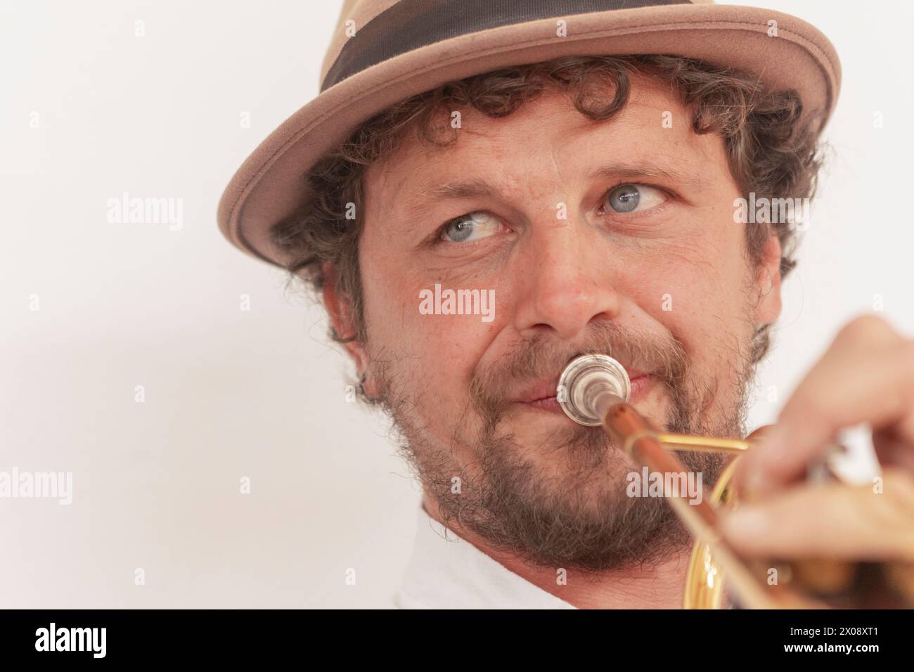 A passionate trumpeter wearing a hat practices his instrument at home, showcasing perseverance and talent in music Stock Photo