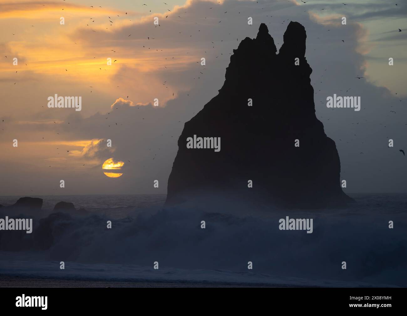 Majestic sea stack silhouetted against a sunset with a backdrop of ...