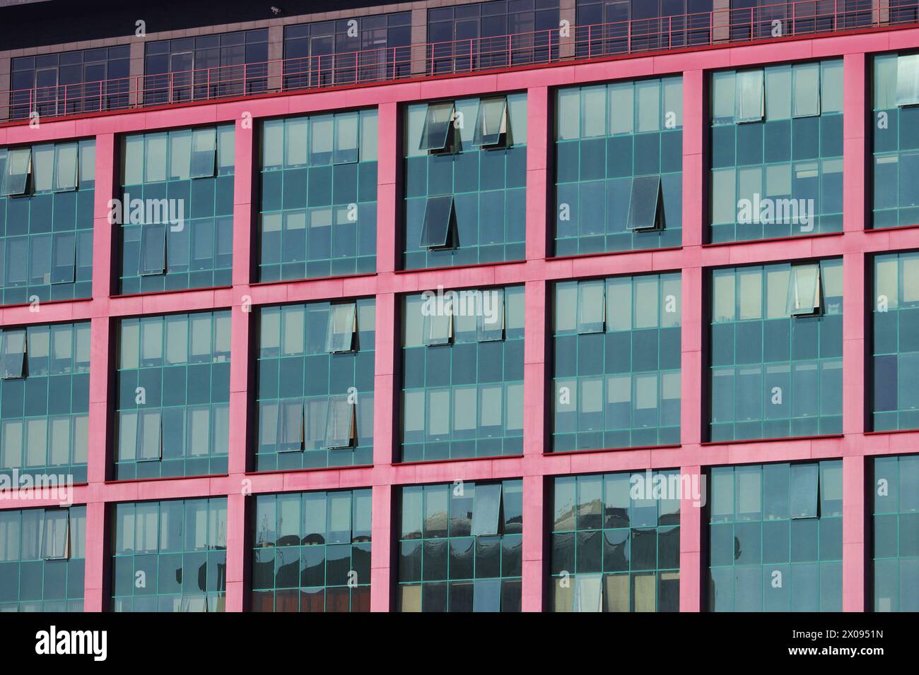Many large windows of a modern office building. Wall of a building with a lot of blue windows and red frames Stock Photo