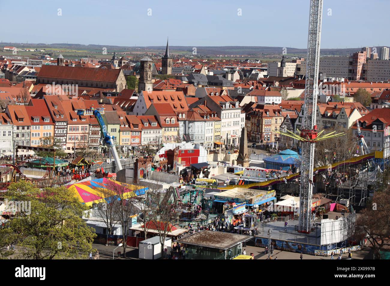 An aerial view of Erfurt city showing a festival where many people gather, playing thrilling rides, flips, and swings, enjoying a fun time in the sun. Stock Photo