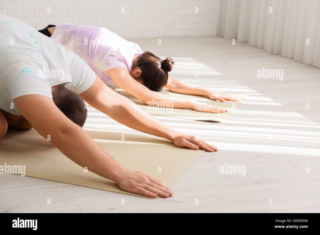 Sporty young couple practicing yoga together in light room, closeup Stock Photo