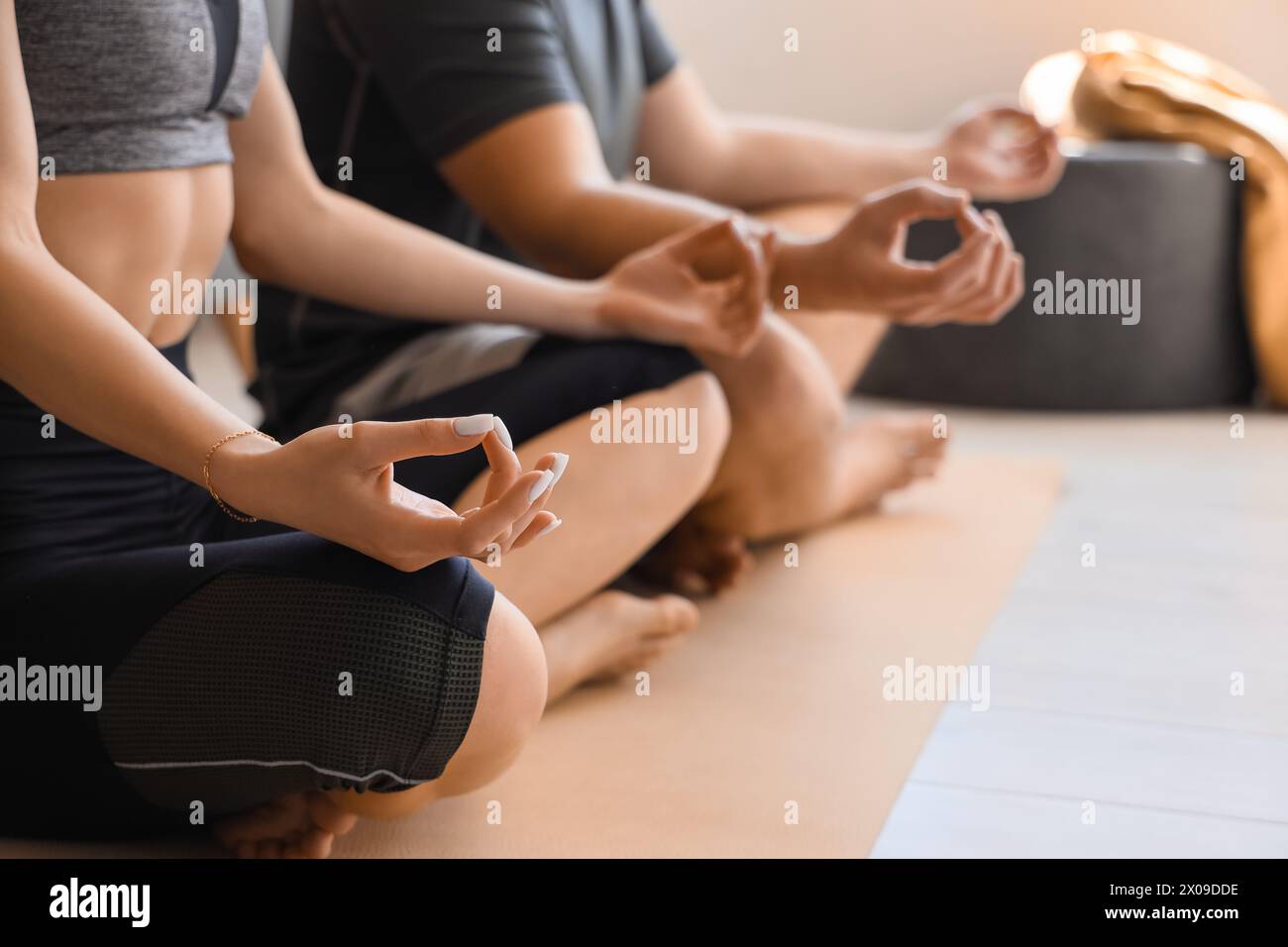 Sporty young couple meditating together in modern living room Stock Photo