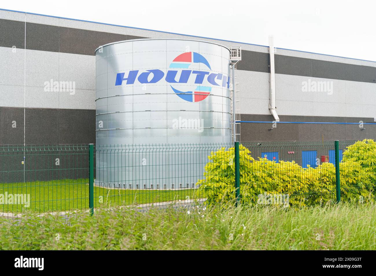 Cambrai, France - May 21, 2023: A large storage tank with the Houlihans logo stands prominently in an industrial setting, surrounded by lush greenery Stock Photo