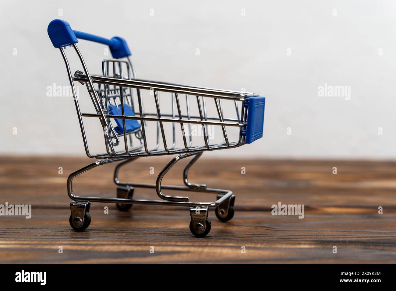 a miniature shopping cart . The concept of consumption, holiday purchases, spending. Stock Photo
