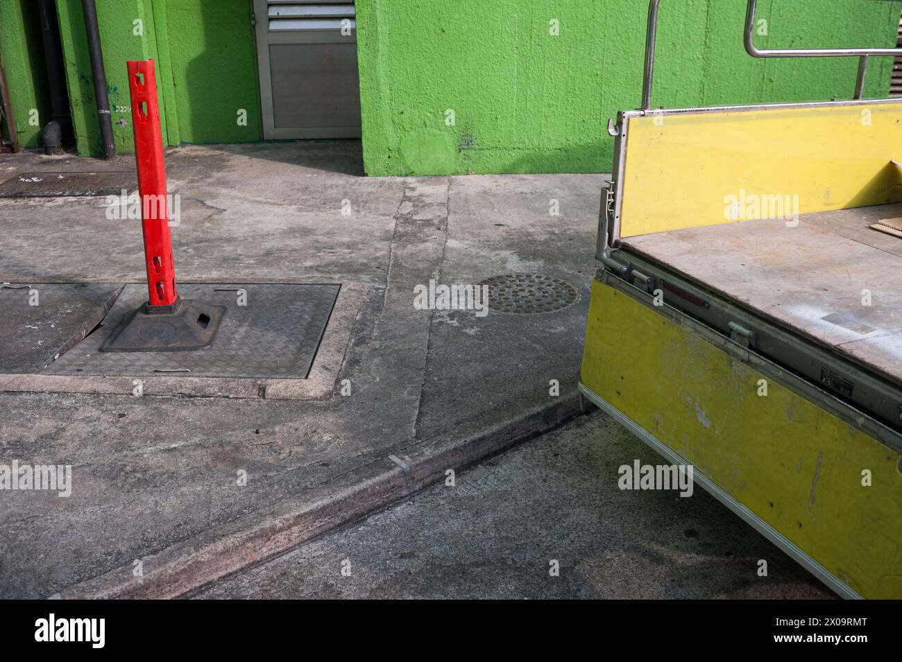 20.10.2017, Singapore, Republic of Singapore, Asia - Abstract street scene with yellow cargo bed of a lorry parked next to a green painted outer wall. Stock Photo