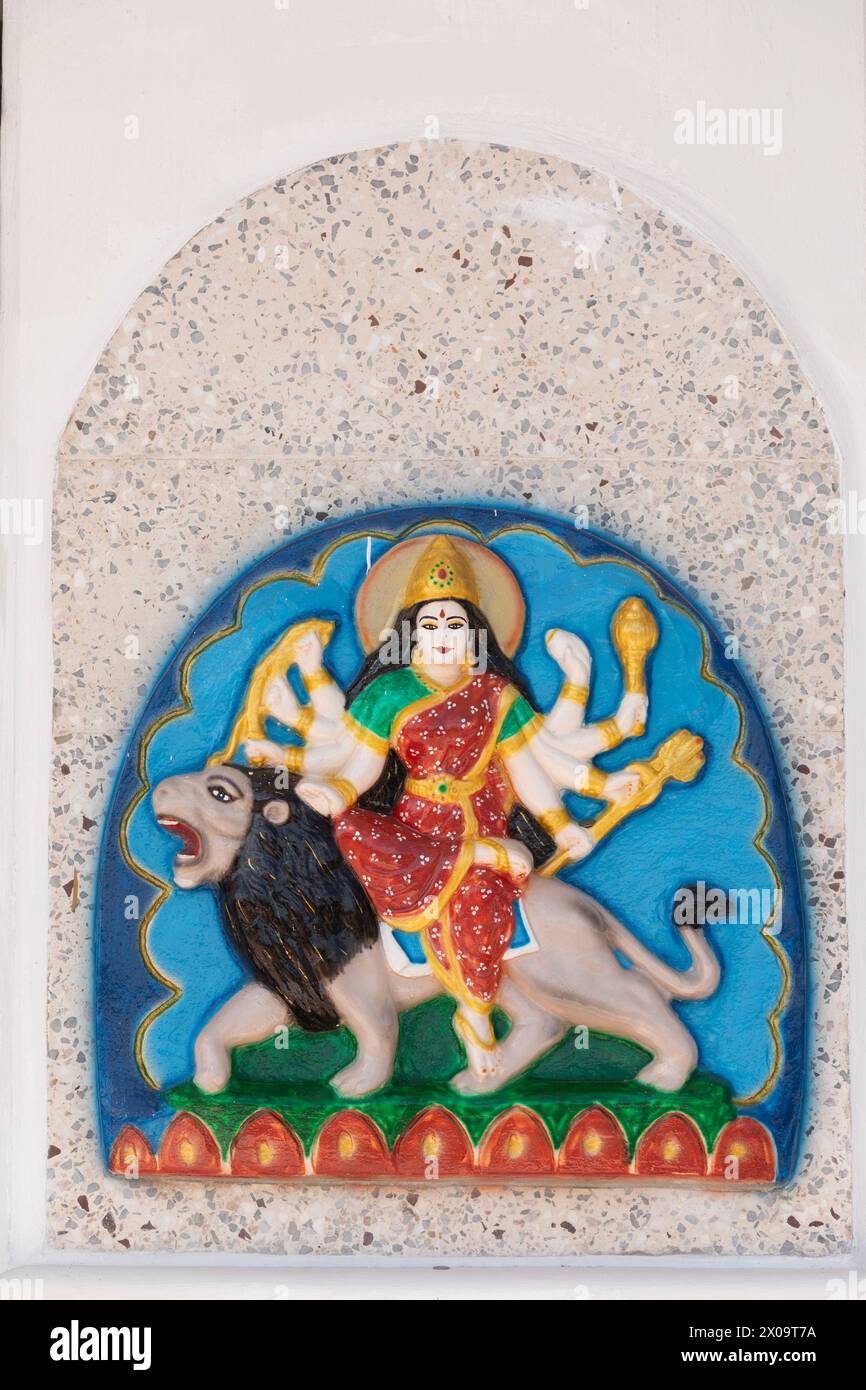 A murti of the Hindu goddess Durga, riding a liion and holding her eight weapons, on an exterior wall of the Temple in the Sea at Waterloo, Carapichai Stock Photo