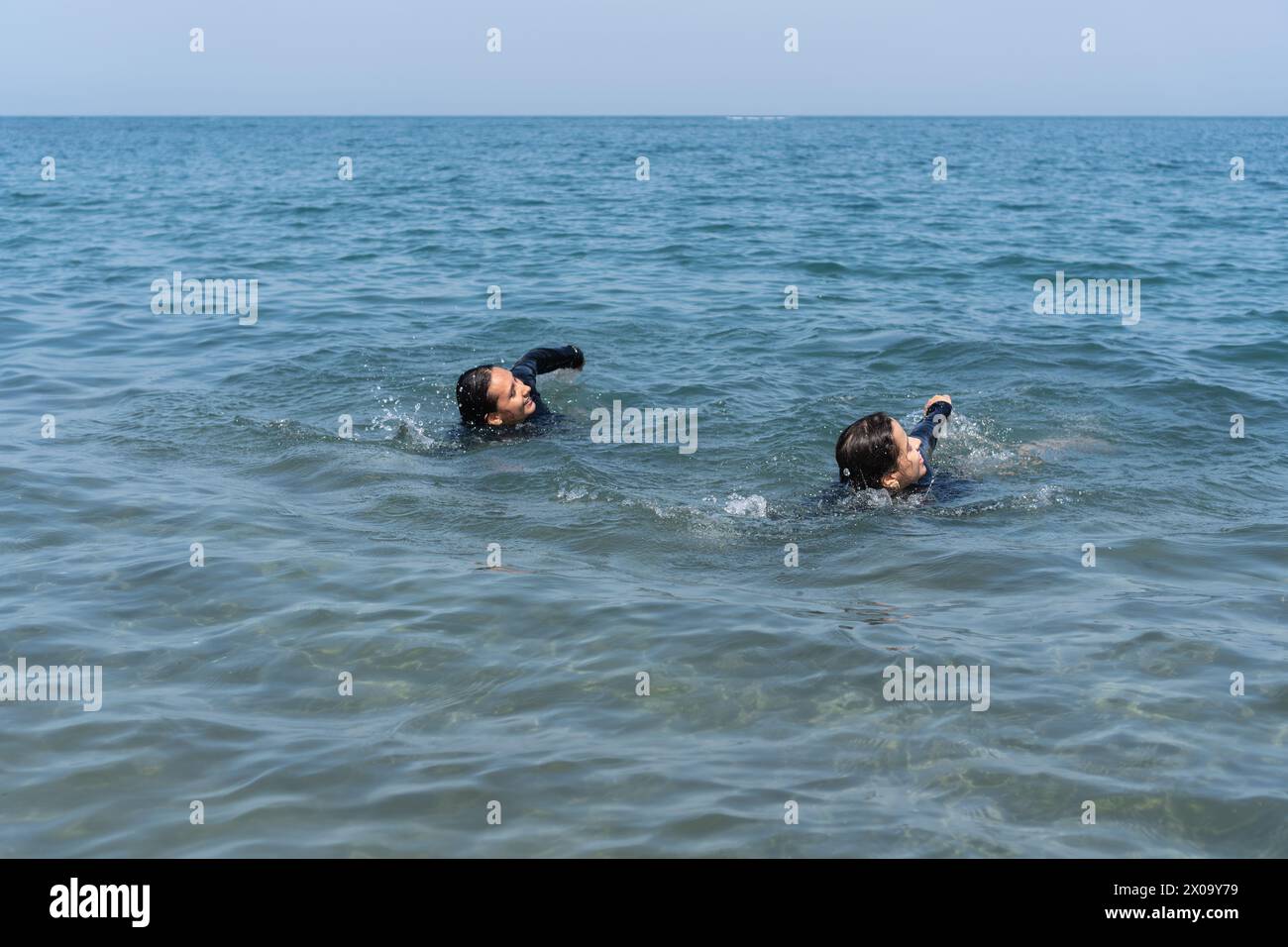 Two individuals swimming in calm ocean waters. Stock Photo
