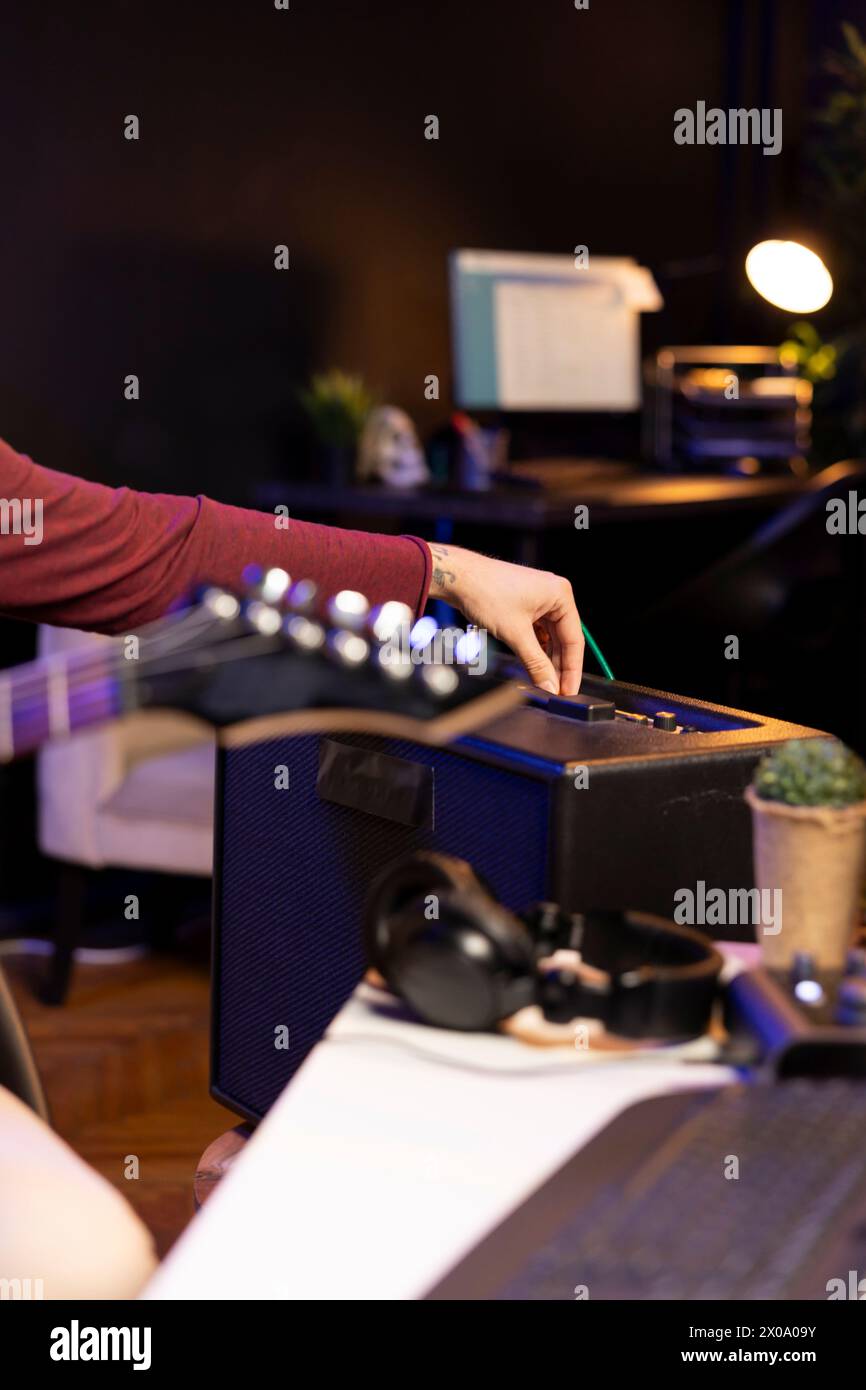 Sound producer adjusting volume levels on home studio amplifier before