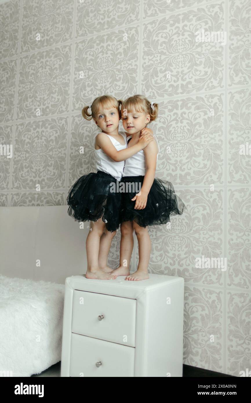 Two young girls embracing each other tightly while standing on top of a ...