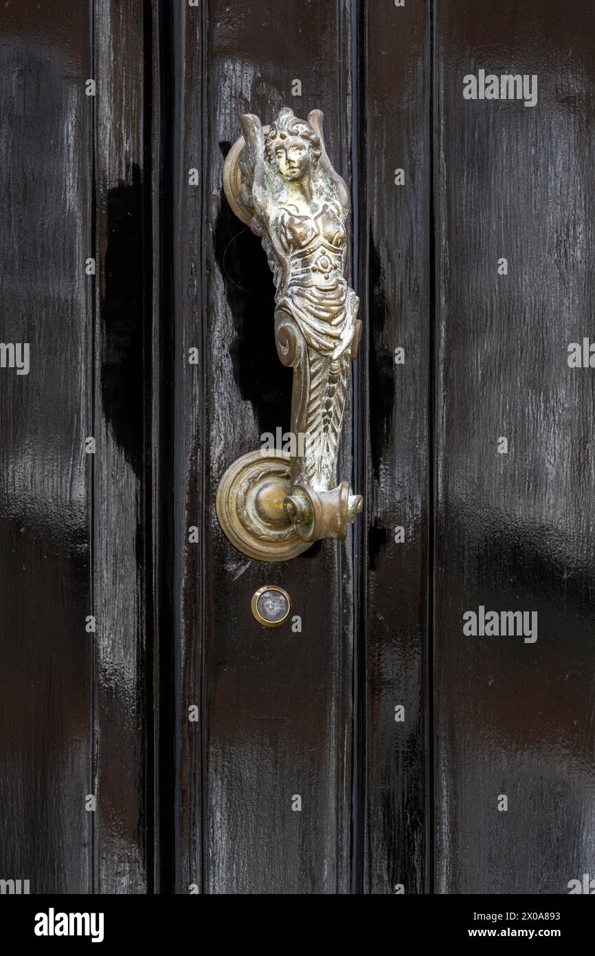Metal door knocker on a black wooden door in the shape of a mermaid Stock Photo