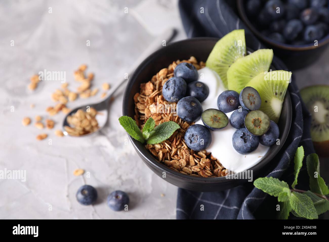 Tasty granola with yogurt, blueberries and kiwi in bowl on gray table, closeup Stock Photo