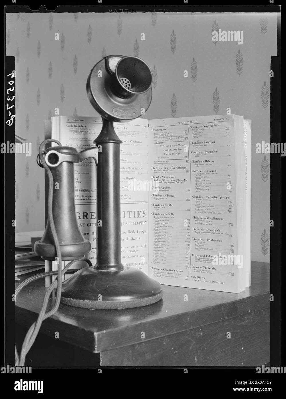 Old-fashioned telephone with printed telephone directory on wooden stand, Dubuque, Iowa, April 1940.  (Photo by John Vachon/Office of War Information) Stock Photo