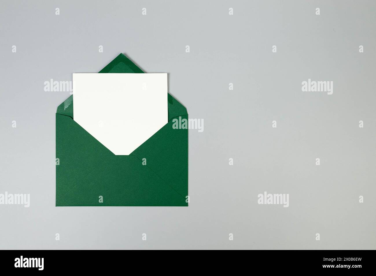 Top view of green envelope, white card on grey background. Post flat lay. Copy space. Stock Photo