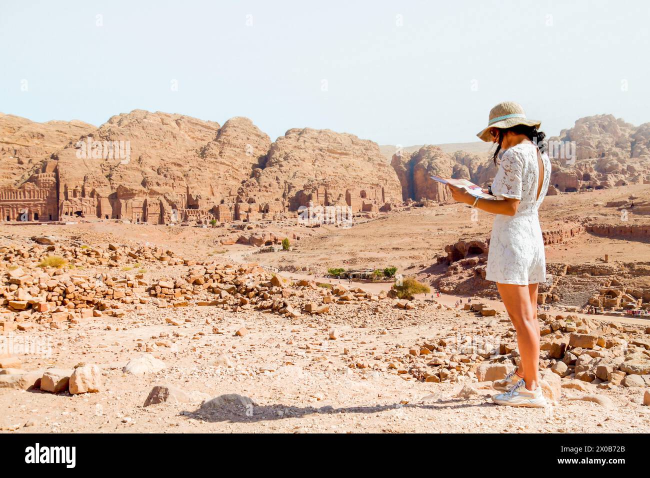 Caucasian woman tourist in white dress read map, plan exploring the sights of the ancient, fabulous city of Petra in Jordan. Concept of planning trip Stock Photo