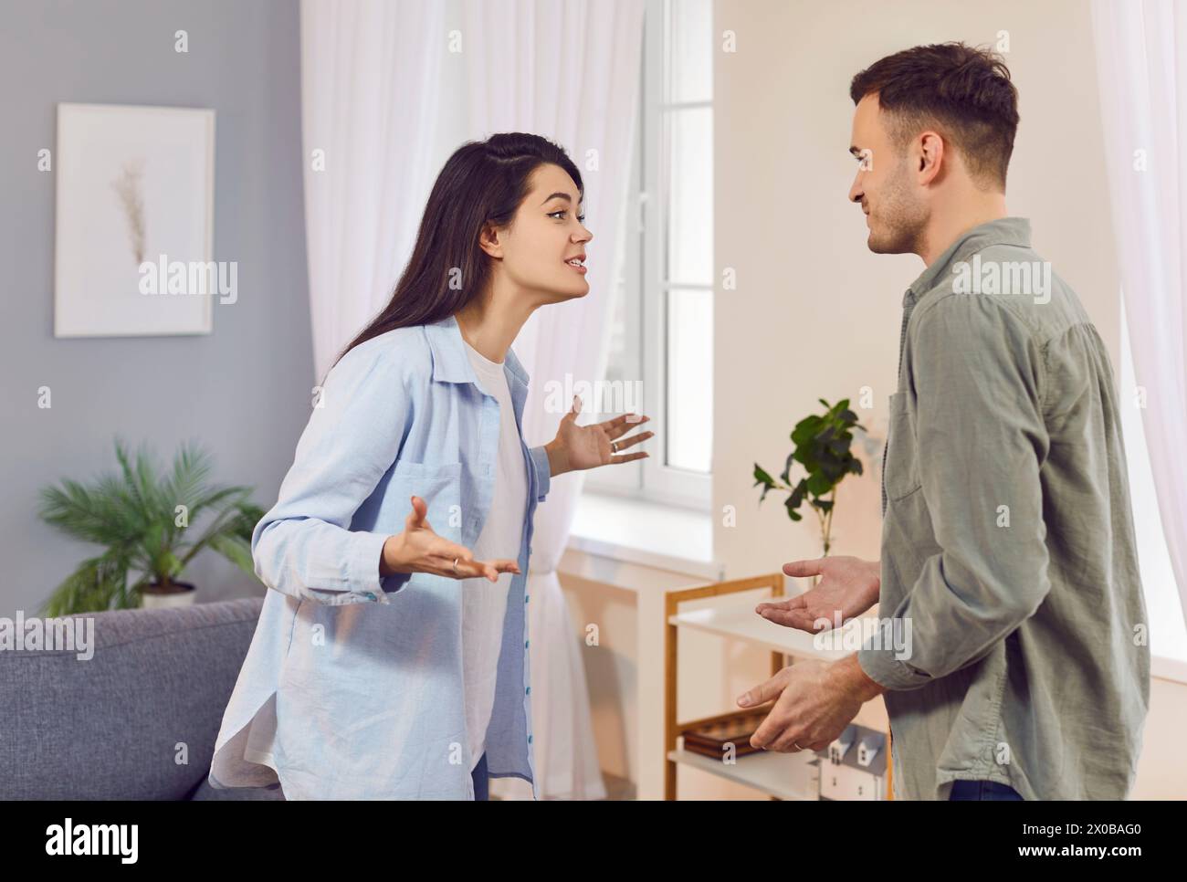 Upset young couple quarreling in the living room at home. Relationship and divorce concept. Stock Photo