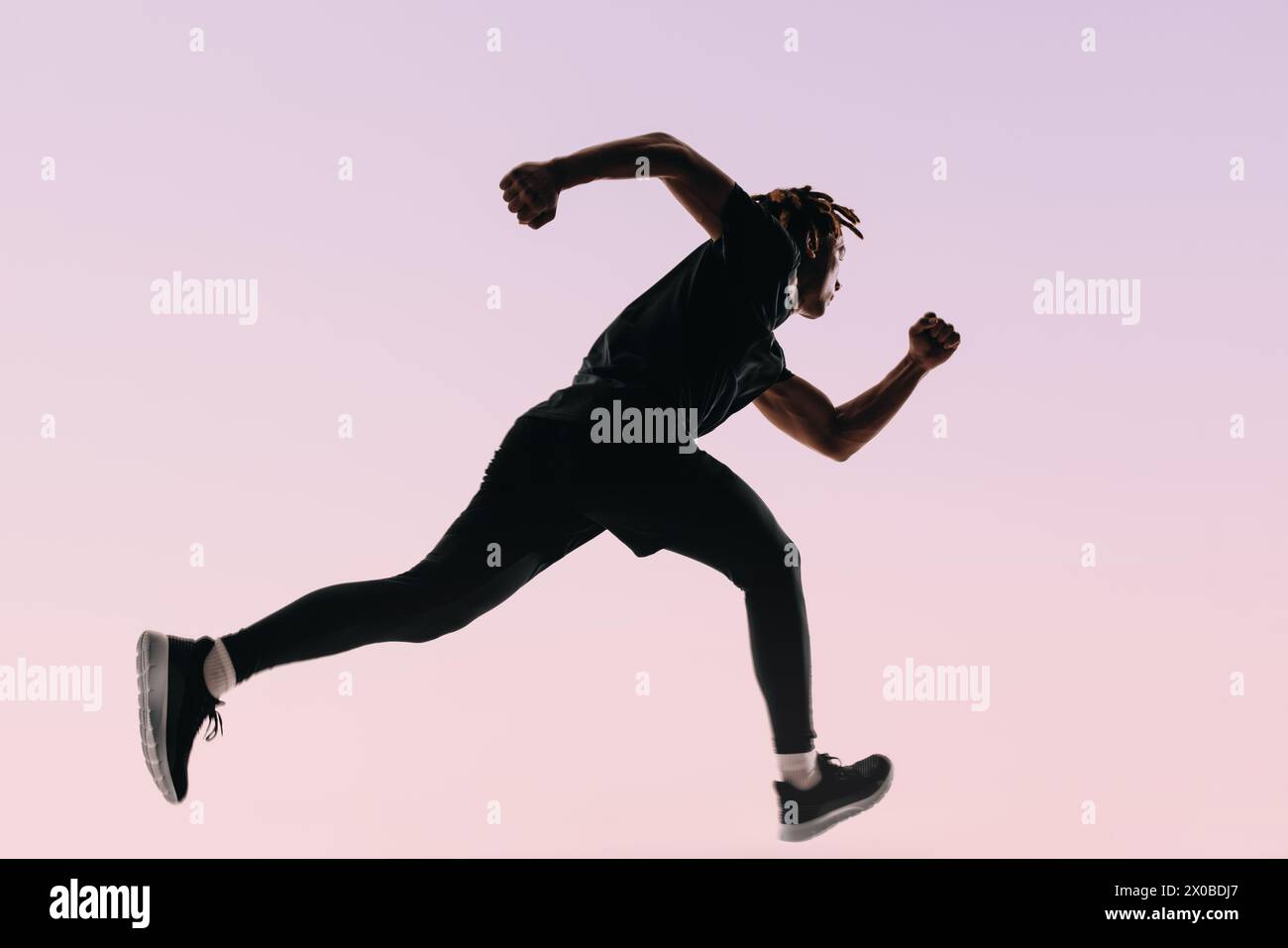 Athlete with dreadlocks showcases athleticism and form in a high-intensity workout. Against a pink backdrop, a silhouette of a runner jumps mid-air, e Stock Photo
