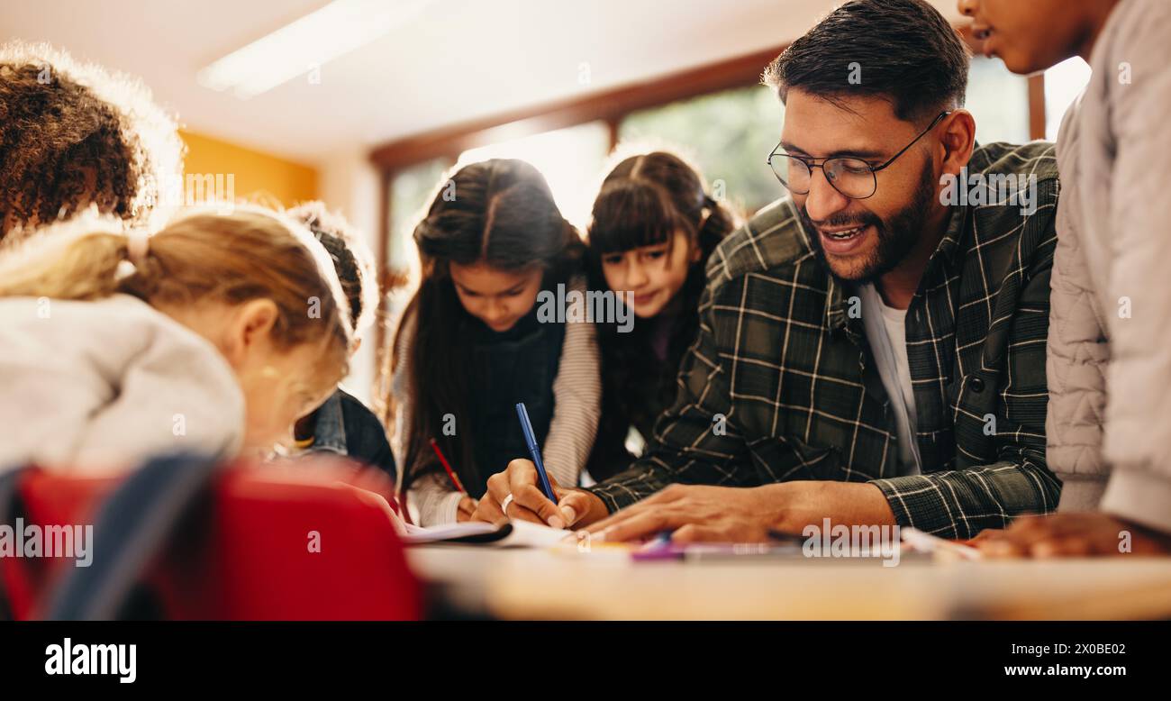 Elementary school educator teaches art to a group of male and female students in a classroom. Class of primary school pupils is paying attention to th Stock Photo
