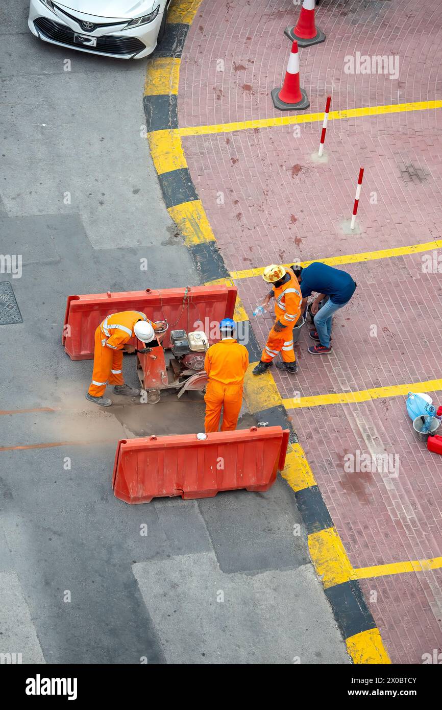 Worker in reflective vest with drill repairing street during roadworks Stock Photo